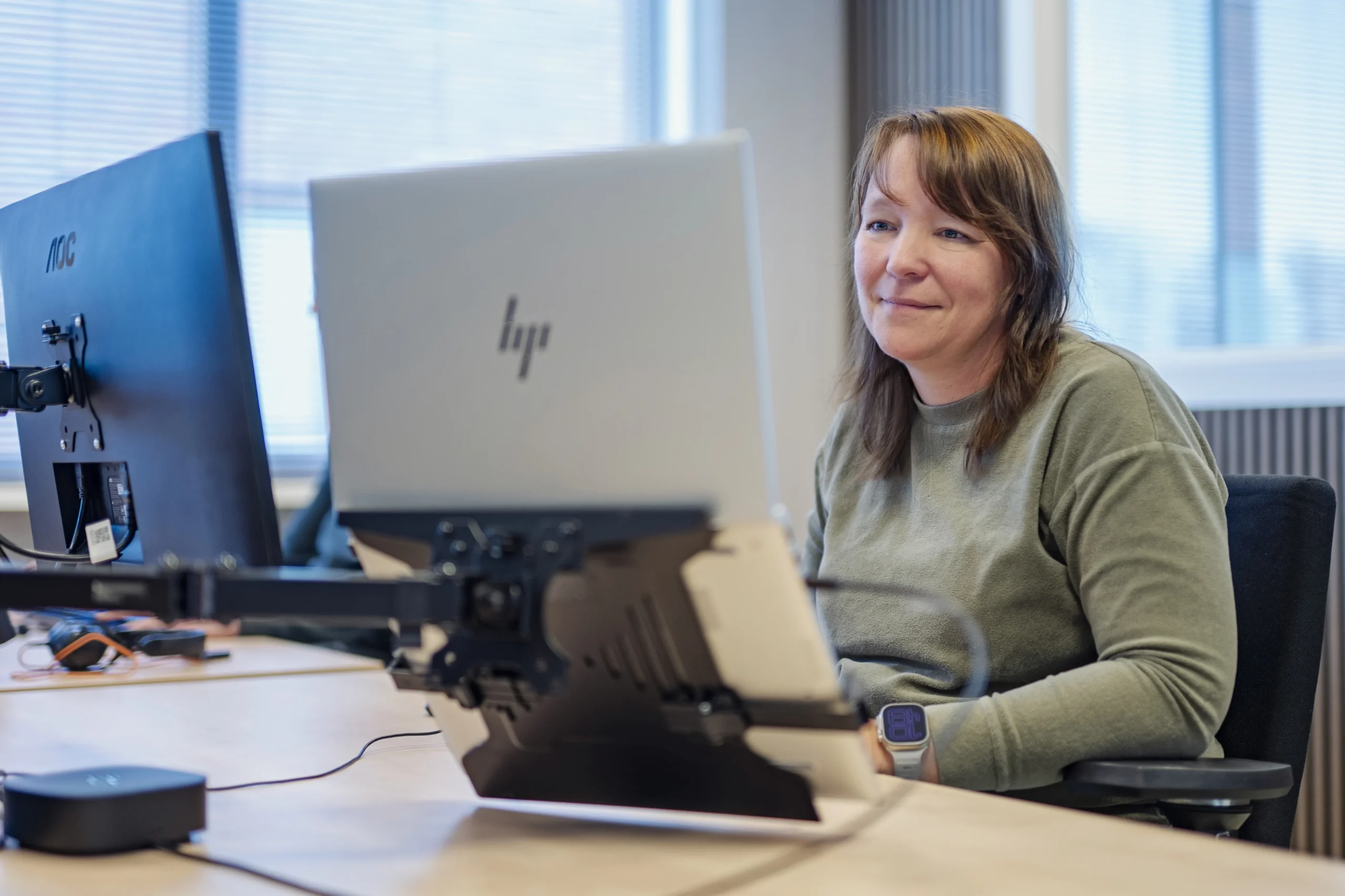 Een persoon die achter een laptop met extra scherm aan het werk is