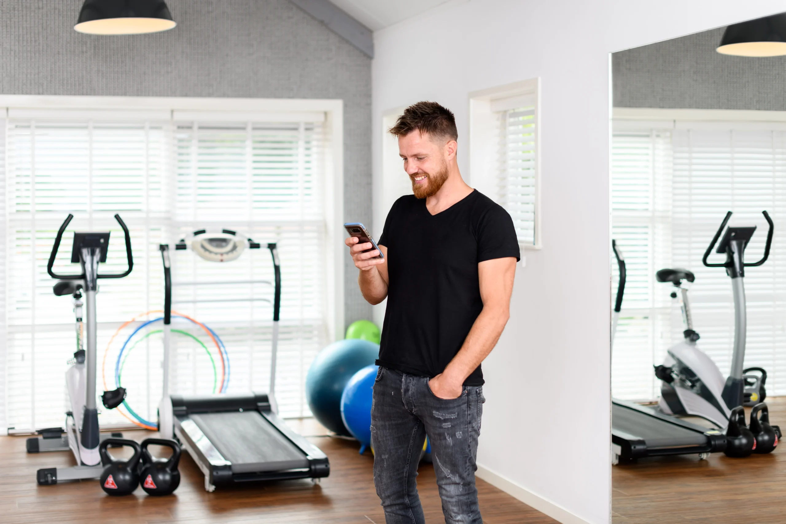 Fysiotherapeut werkt in de sportzaal op zijn mobiel
