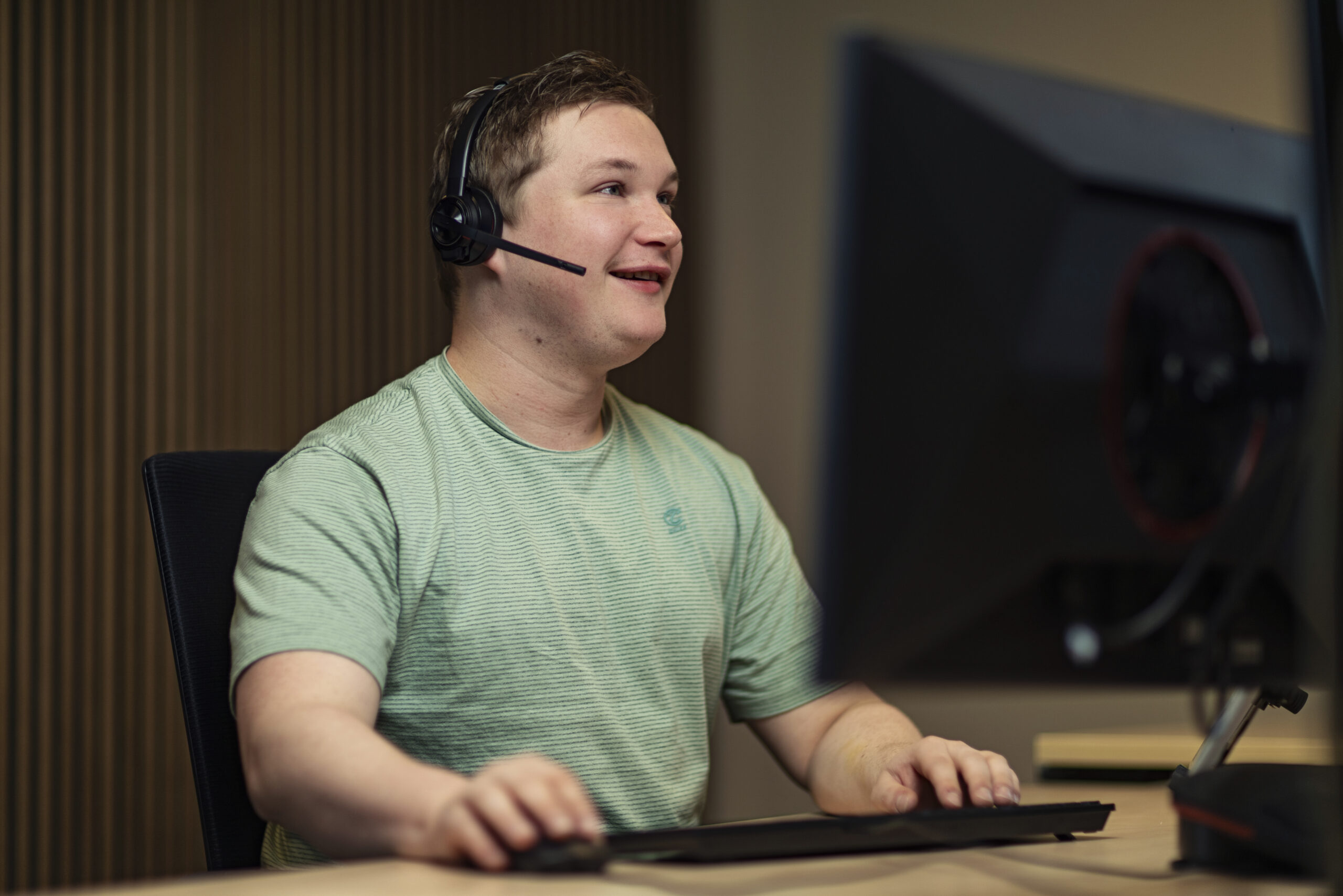 Man met een headset achter een computer.